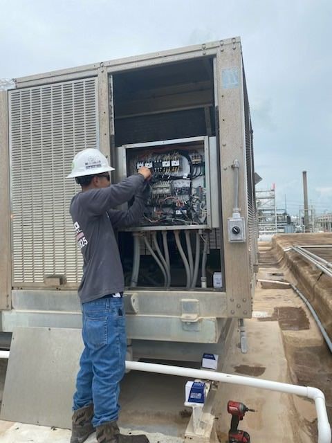 Two men are working on a machine on a construction site.