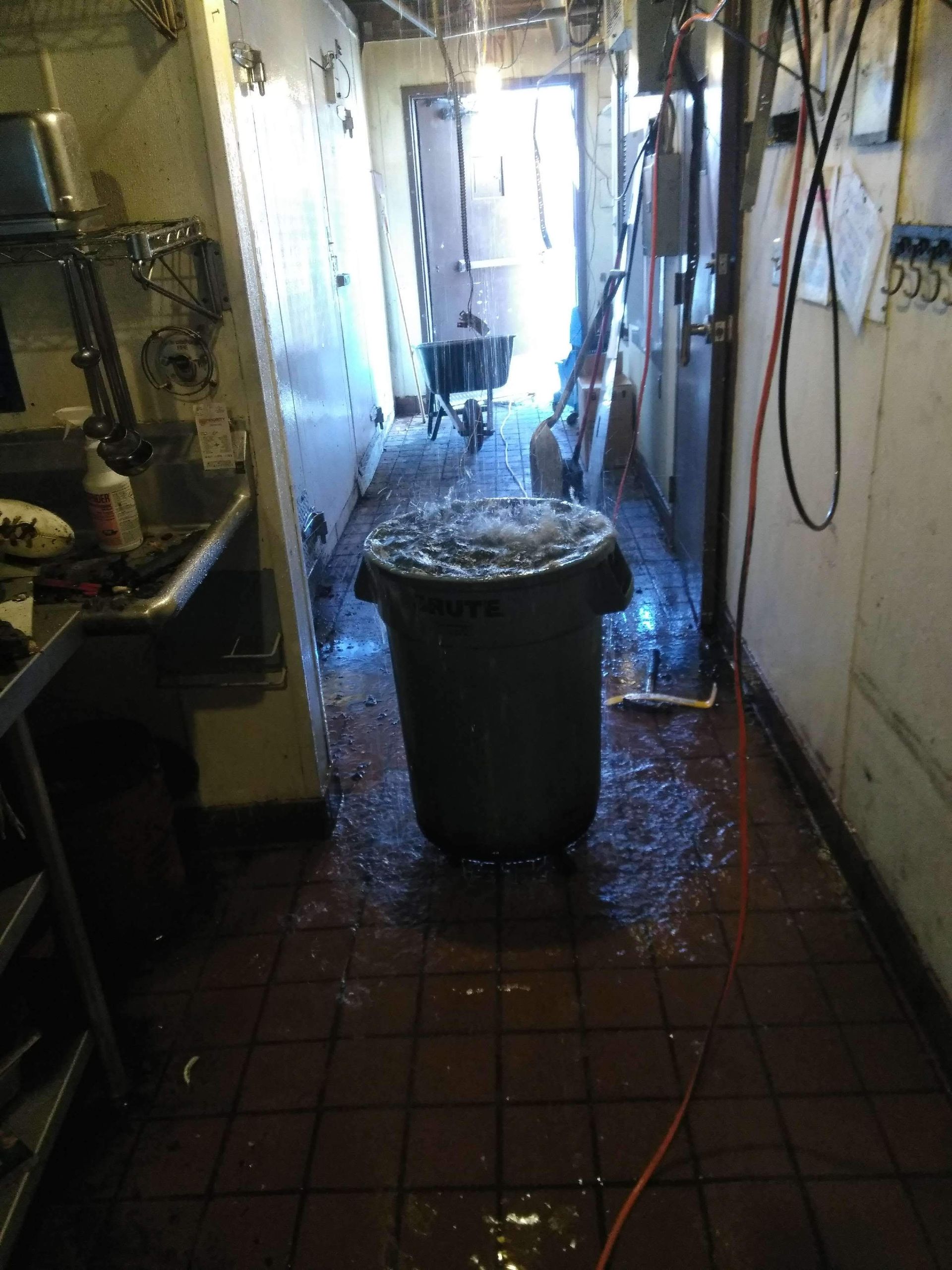 A trash can is sitting in the middle of a kitchen filled with water.