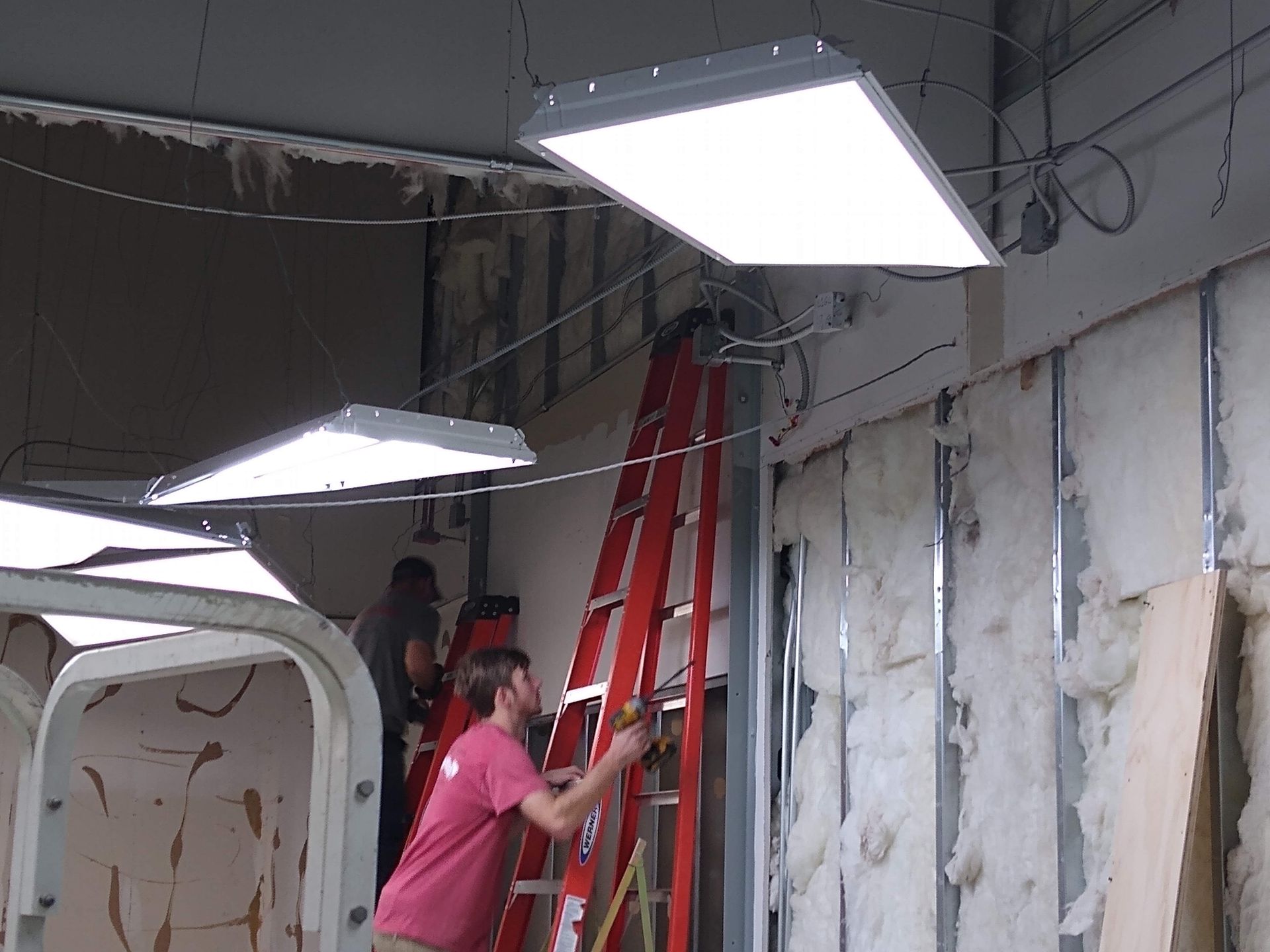 A man on a ladder is working on a wall