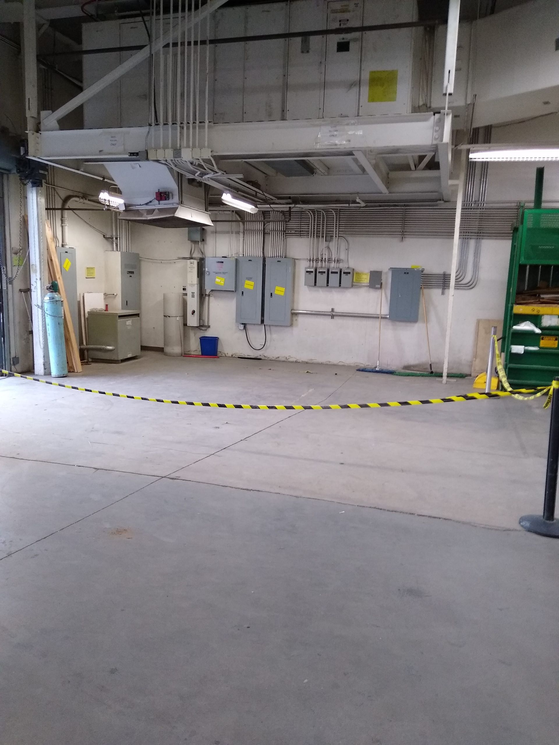 An empty warehouse with a green machine in the middle