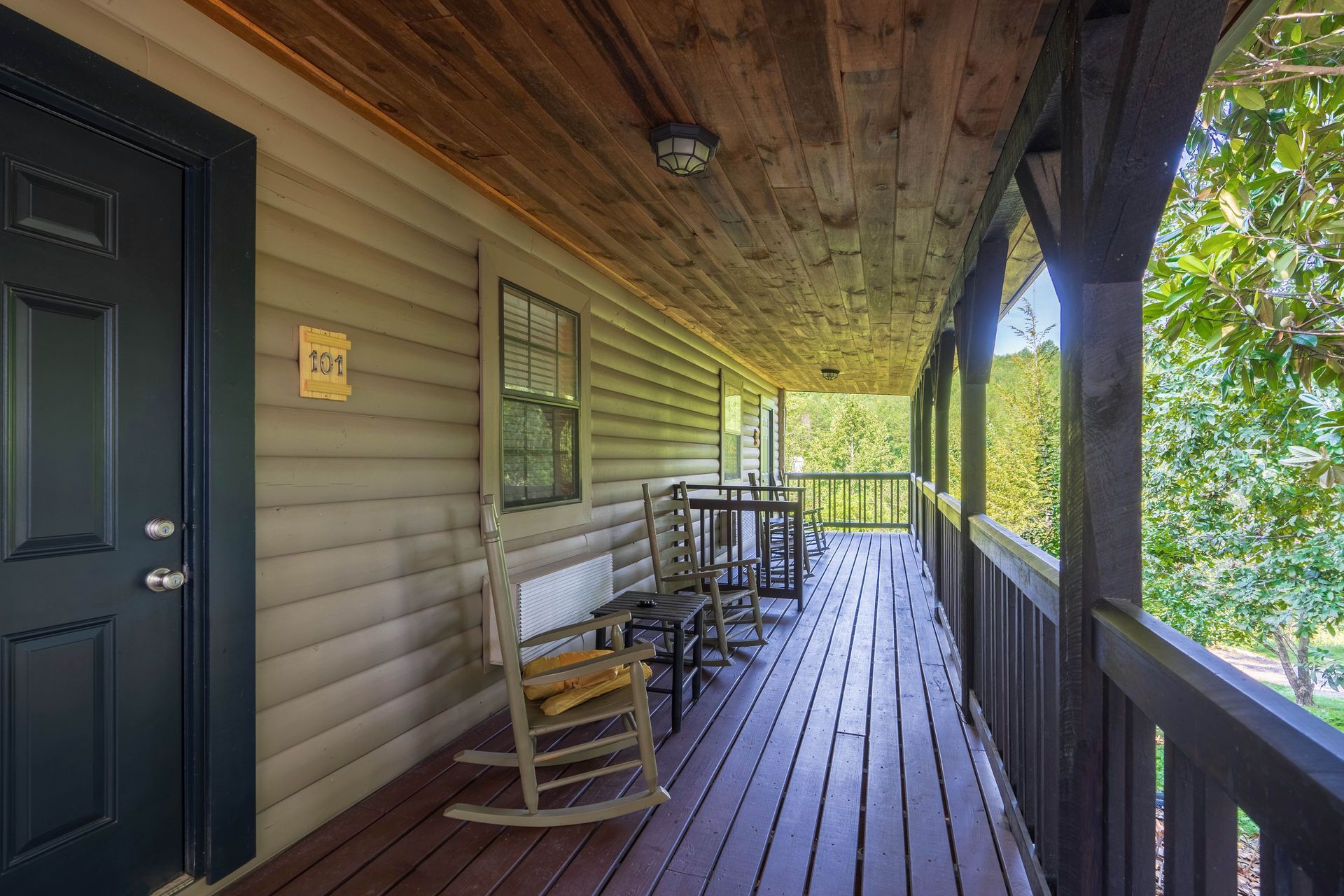 Covered porch with rocking chair and table. Wooden siding and ceiling.
