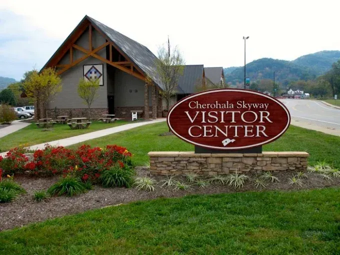 Cherohala Skyway Visitor Center sign in front of a building with brown exterior and green grass.