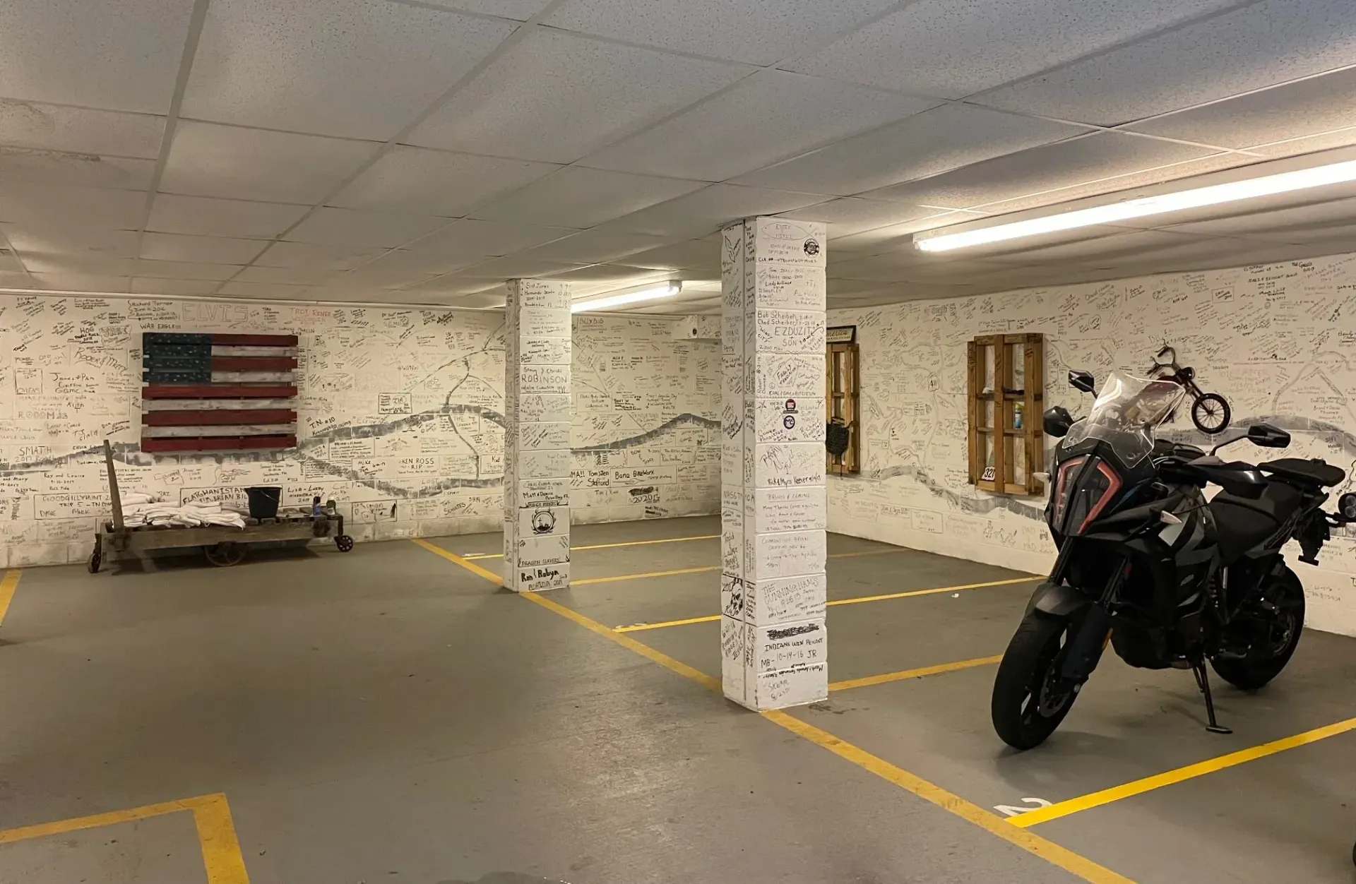 Motorcycle parked in a garage space marked with yellow lines. American flag on the wall.