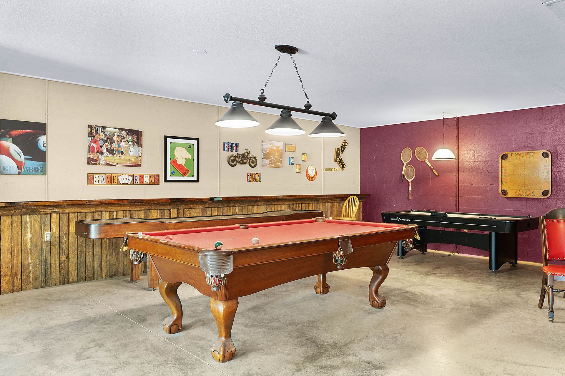 A recreation room with a pool table, foosball, and decorative wall art.