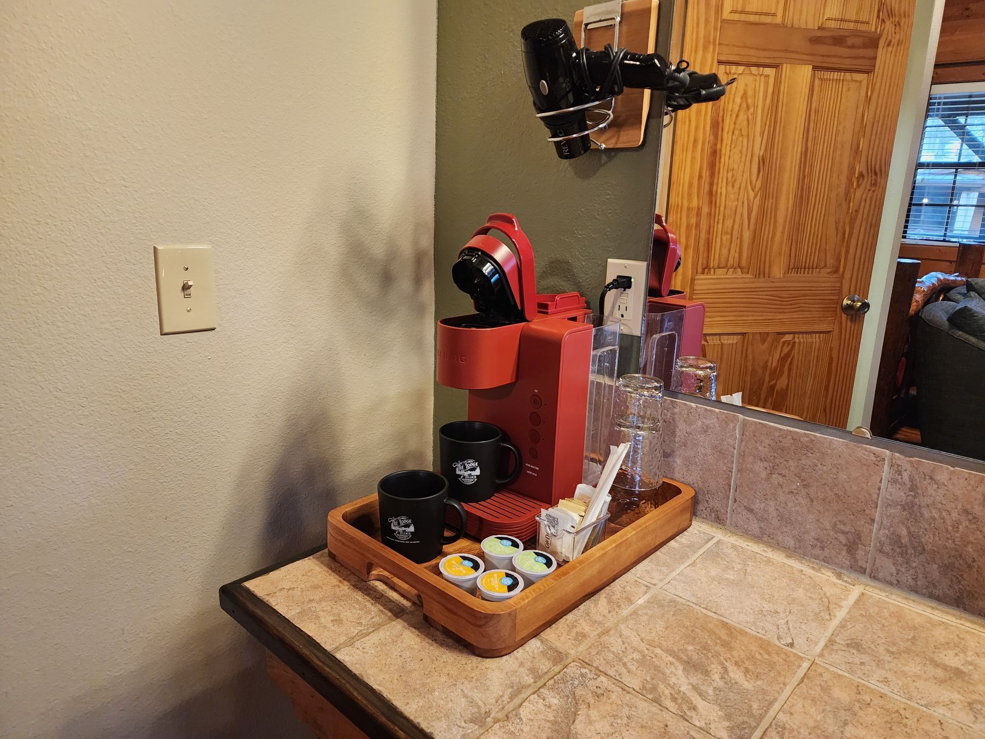 A red Keurig coffee maker on a countertop with cups, pods, and accessories.