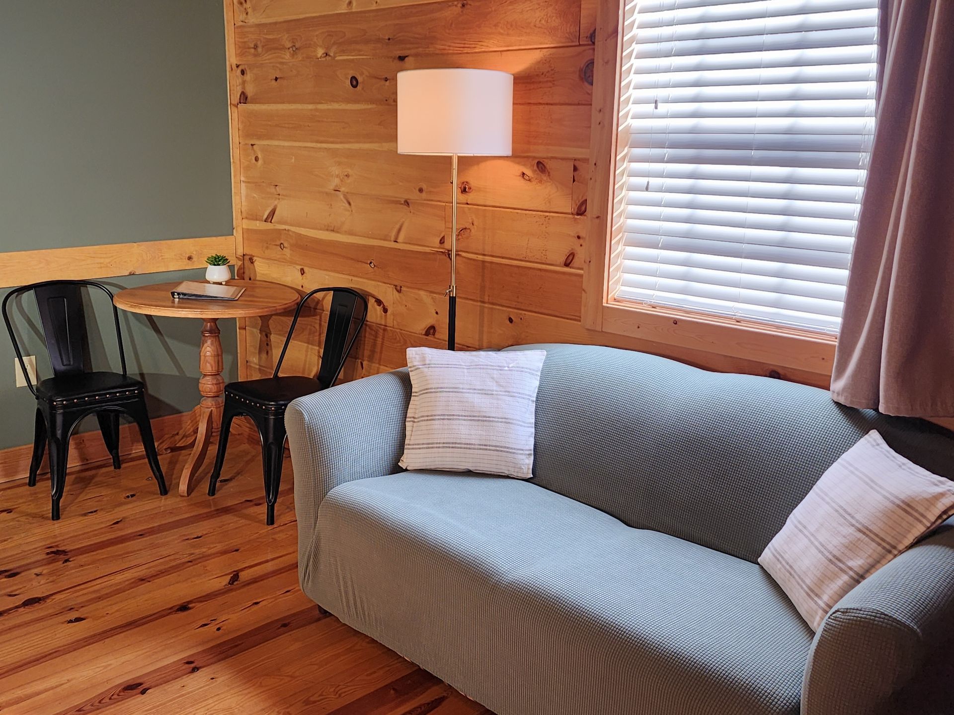 Cozy living room with a couch, table with chairs, and a window with blinds.