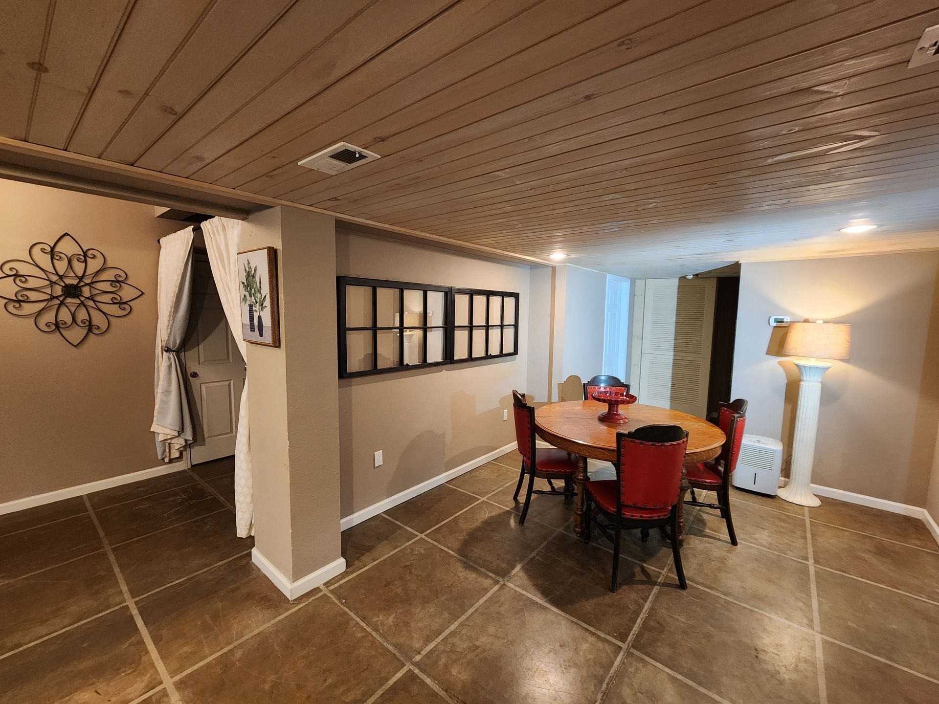 Dining room with a round table, red chairs, and a decorative wall feature.