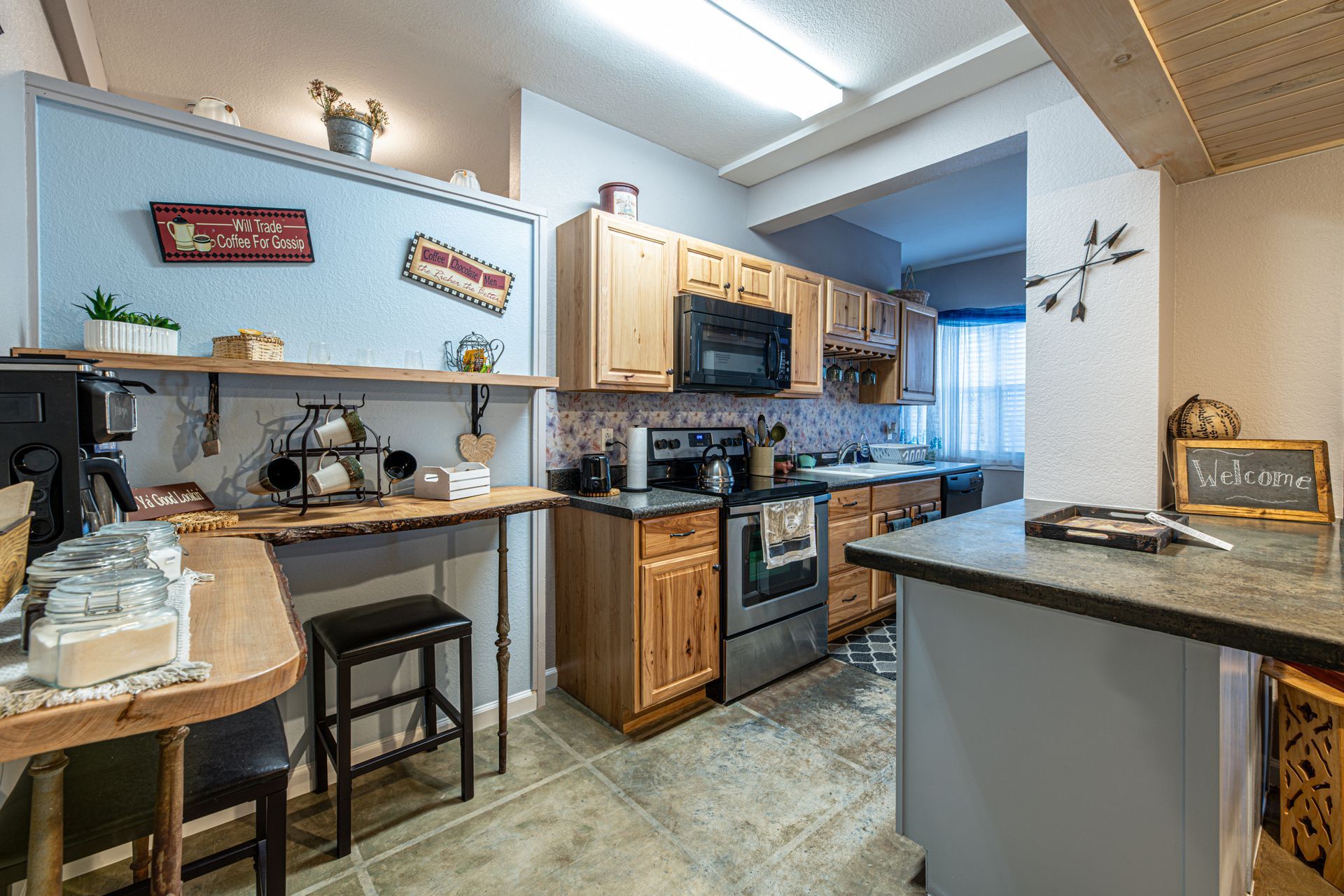 Kitchen with light wood cabinets, gray countertops, and a small island.