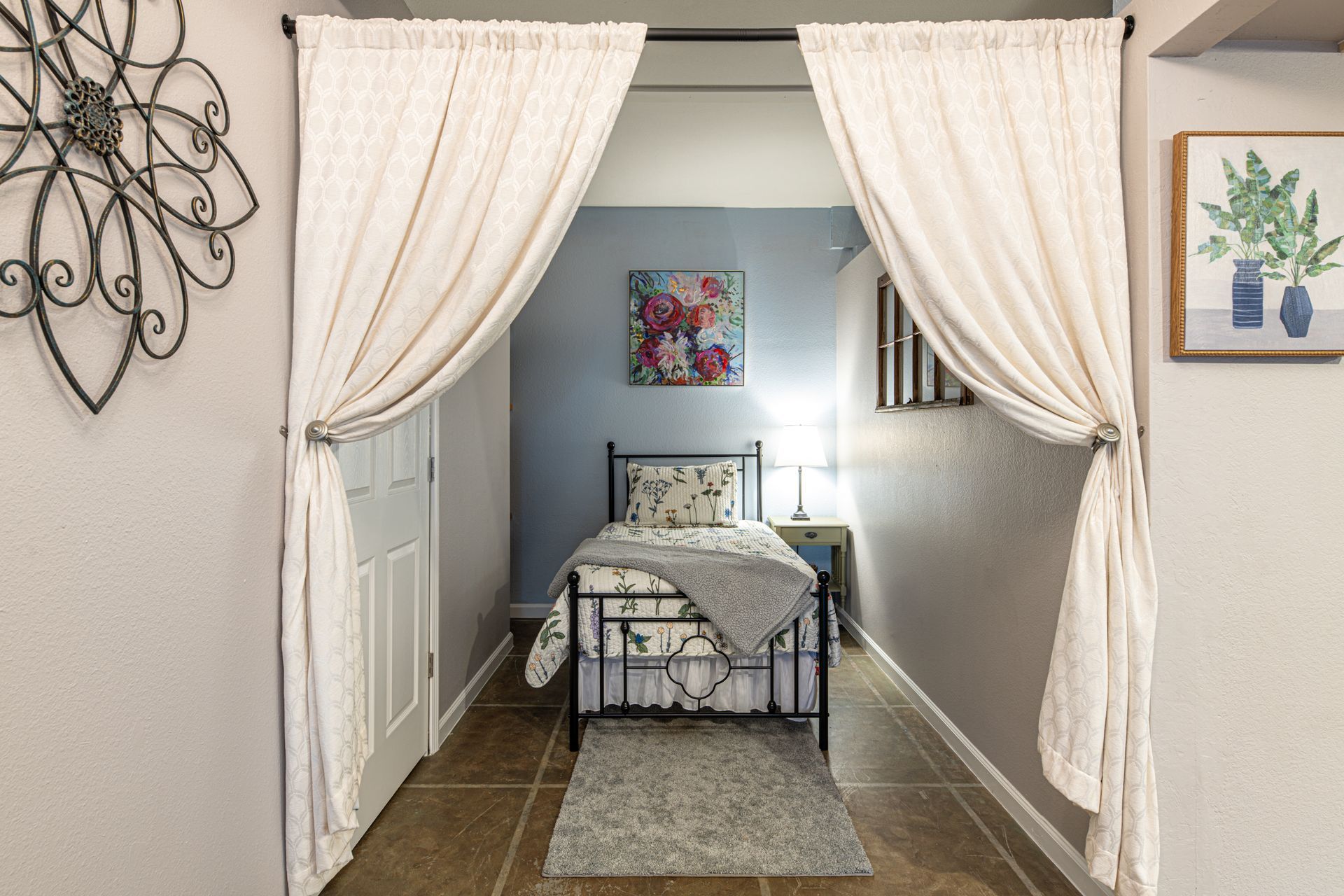 Bedroom alcove with bed, gray rug, and sheer curtains.