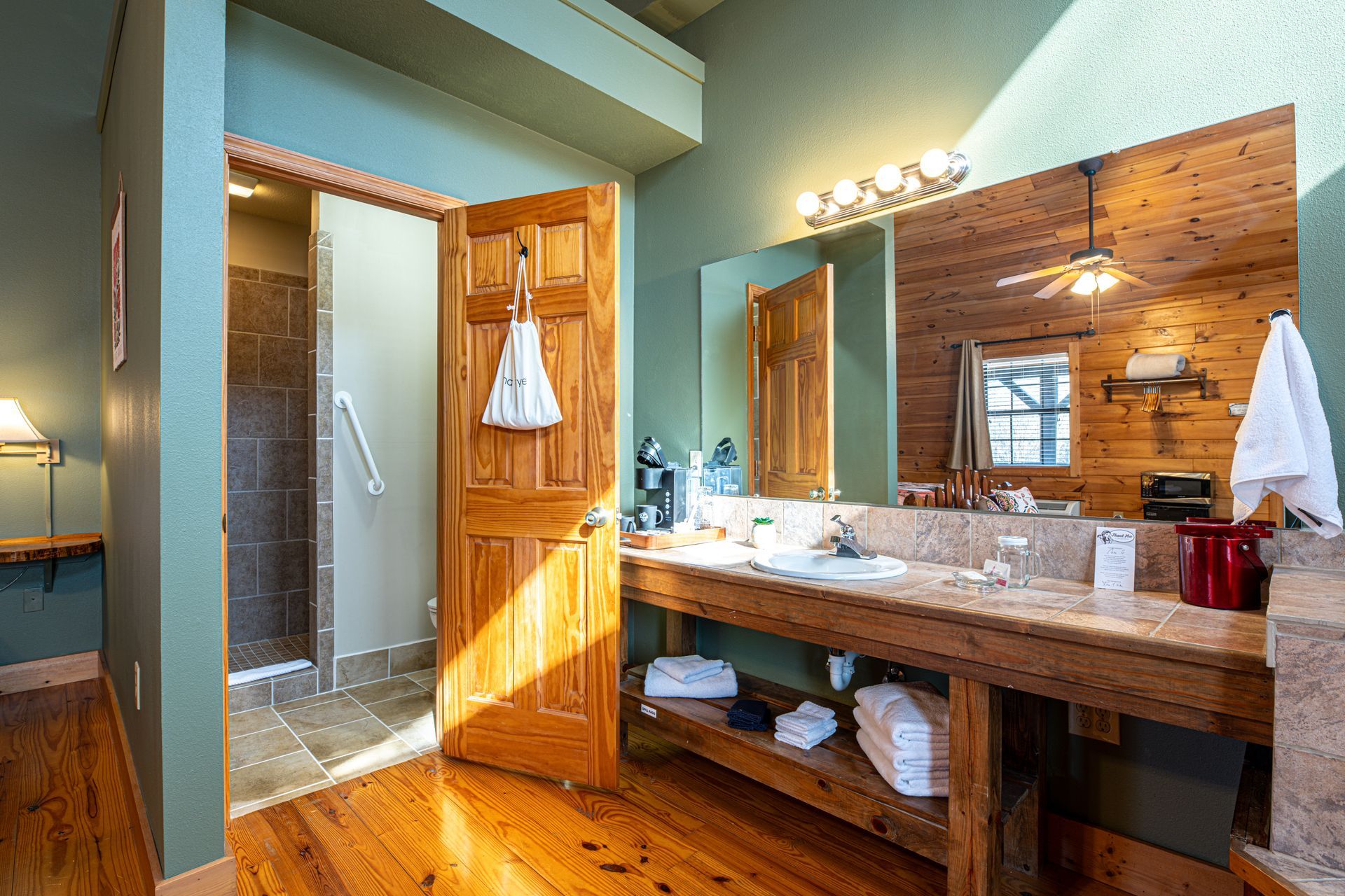 Bathroom with wood vanity, shower, and turquoise walls.