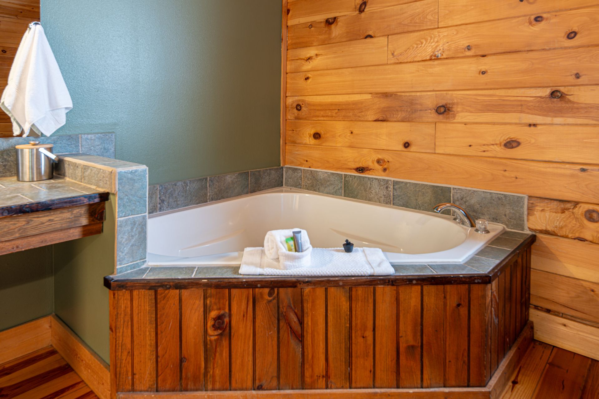 Jacuzzi tub in a wood-paneled bathroom with a countertop and towel.