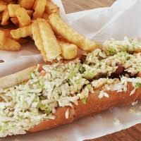 Hot dog on a bun with coleslaw, served with a side of french fries.