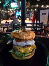 Burger impaled with a knife on a black plate, in a bar setting.