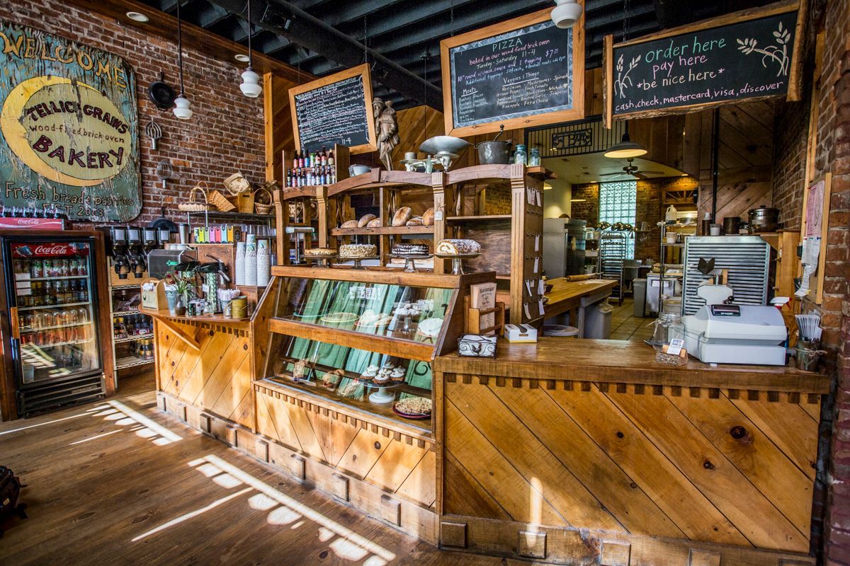 Interior of a bakery with wooden counters, shelves displaying baked goods, and chalkboard menus.