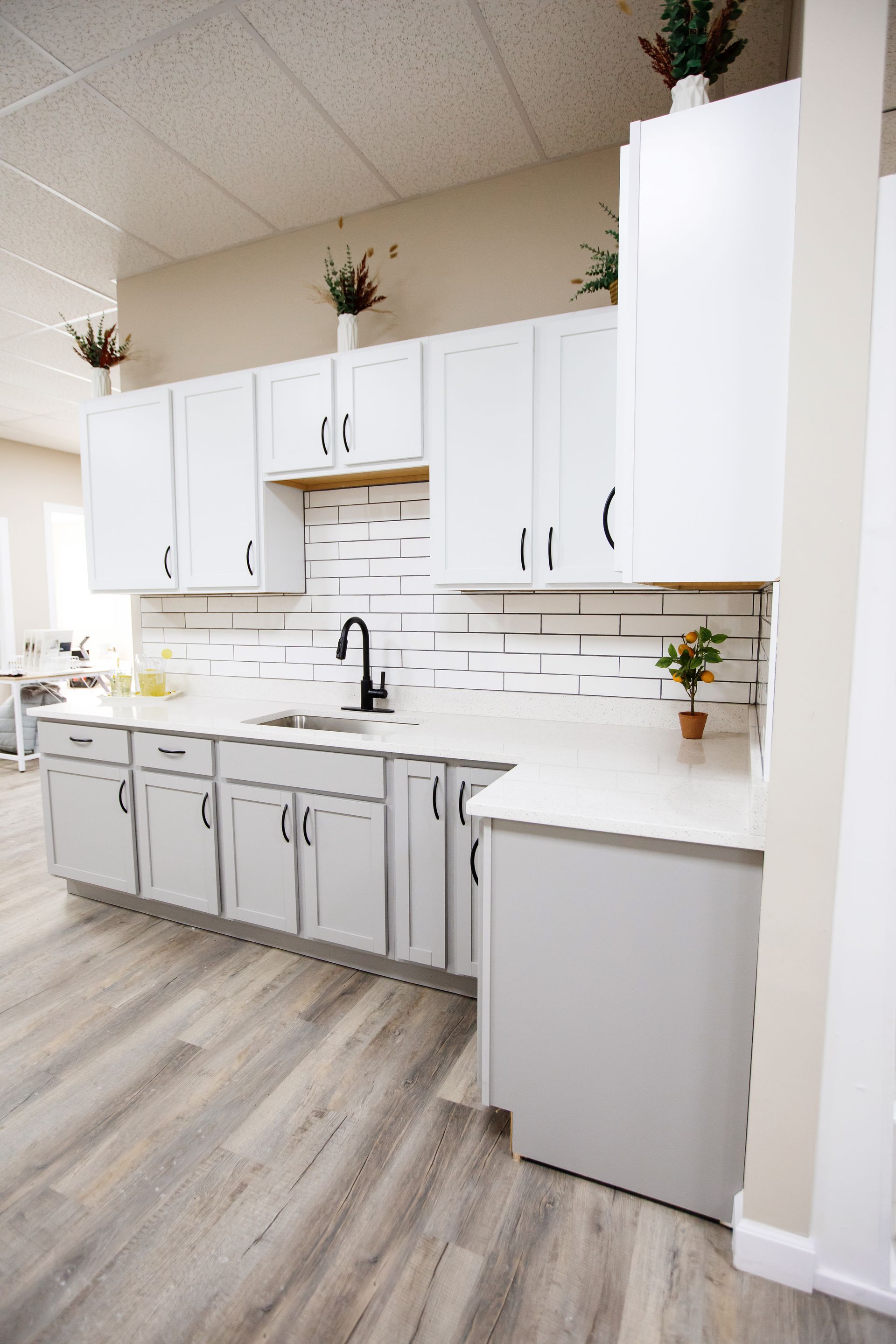 A kitchen with gray cabinets and white counter tops