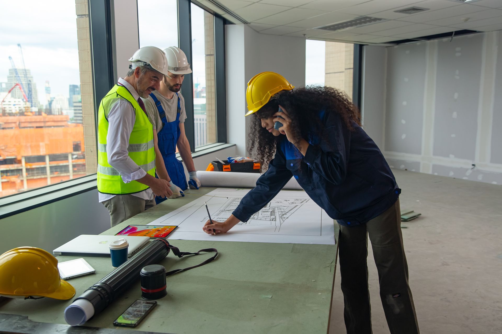 A group of construction workers are looking at a blueprint on a table.