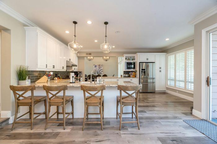 A kitchen with a large island , stools and a refrigerator.