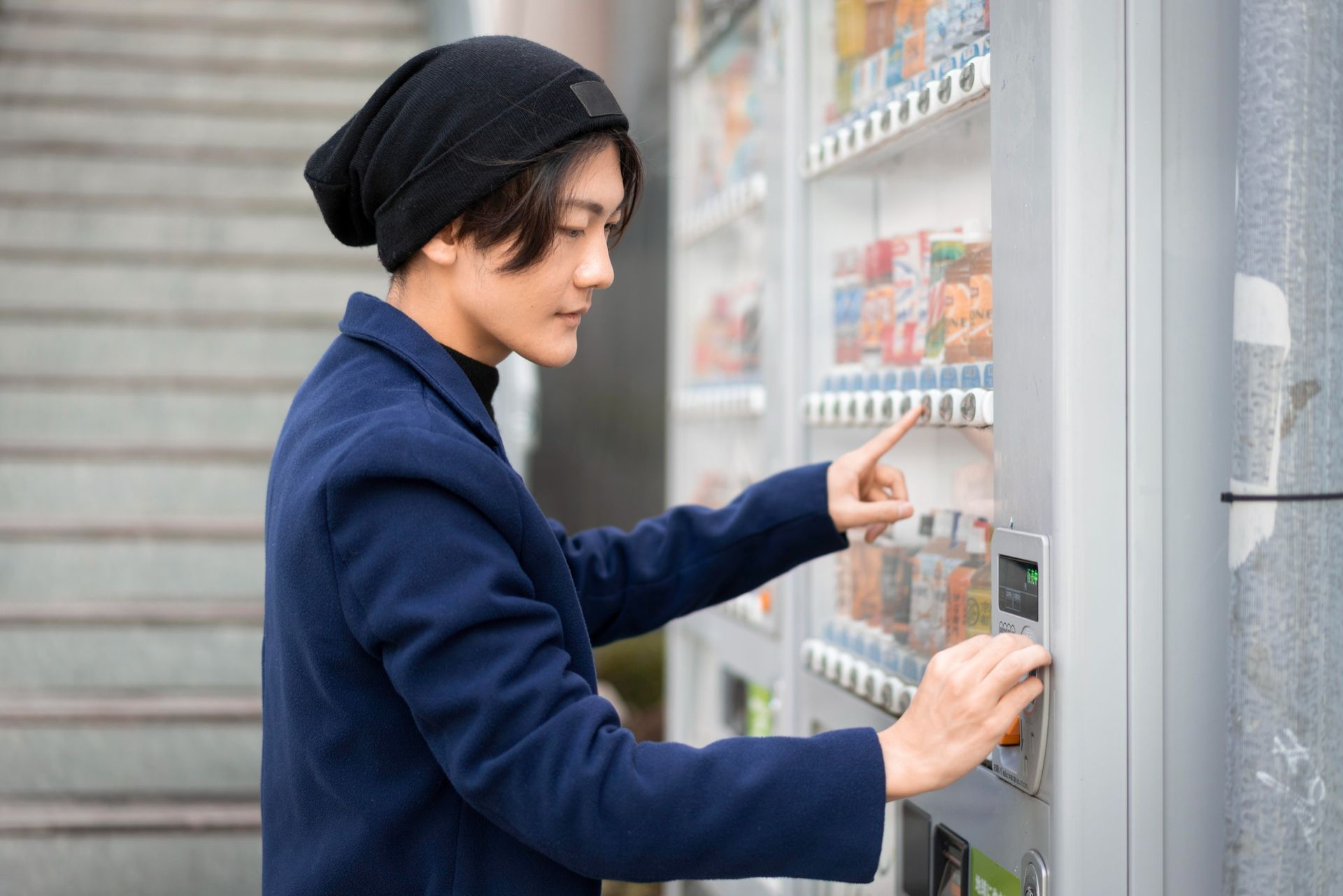 a man is using a vending machine to buy a drink .