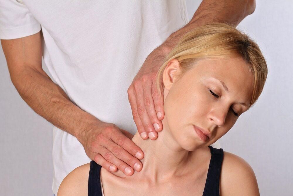 A Woman Is Getting A Neck Massage From A Man — Trinity Family Chiropractic In Brinsmead, QLD