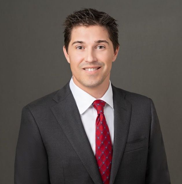 A man in a suit and tie is smiling for the camera