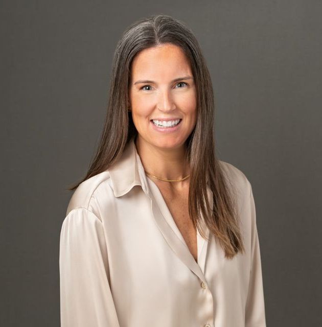 A woman in a beige shirt is smiling for the camera.