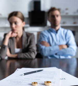 A man and a woman are sitting at a table with their arms crossed.