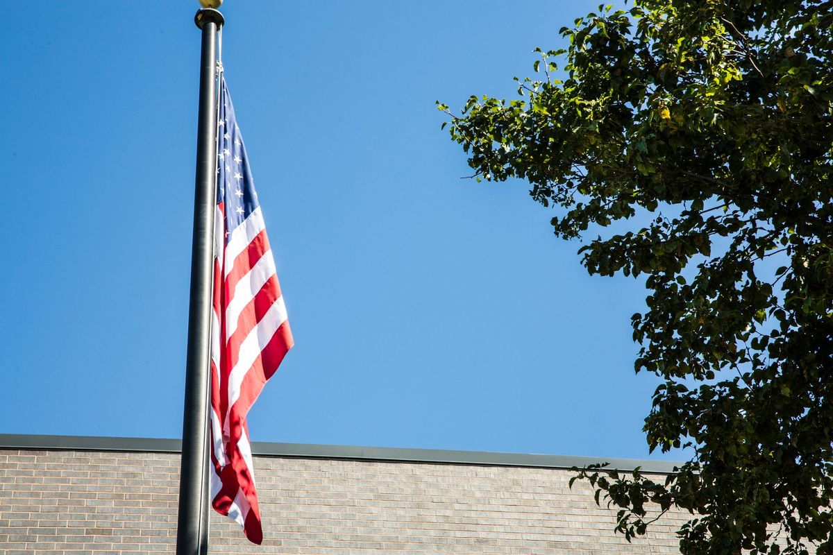 An american flag is flying on a pole in front of a building