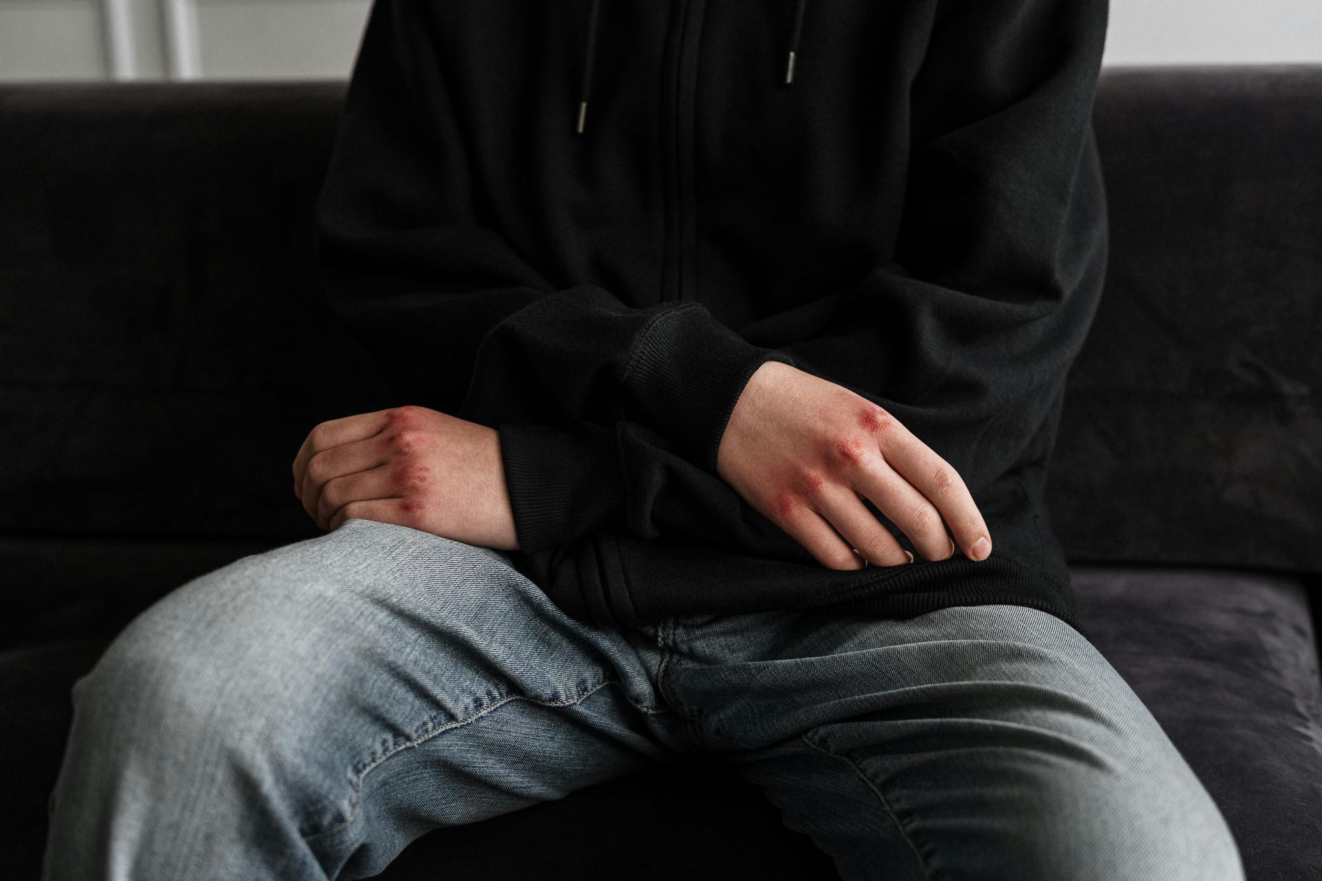 A man is sitting on a couch with his hands on his knees.