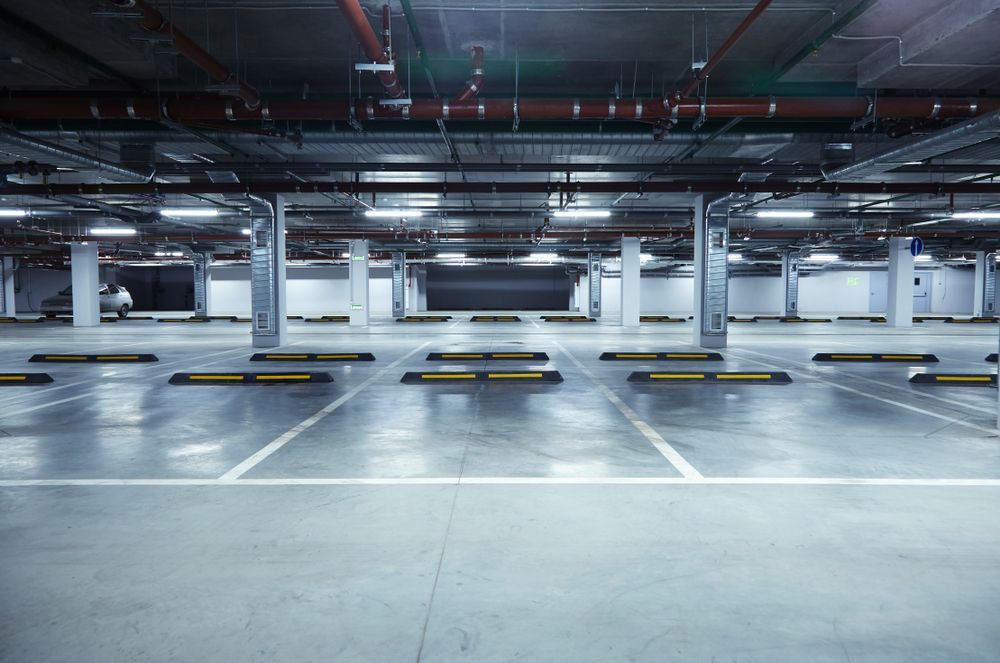 An empty underground parking garage with a car parked in the background.