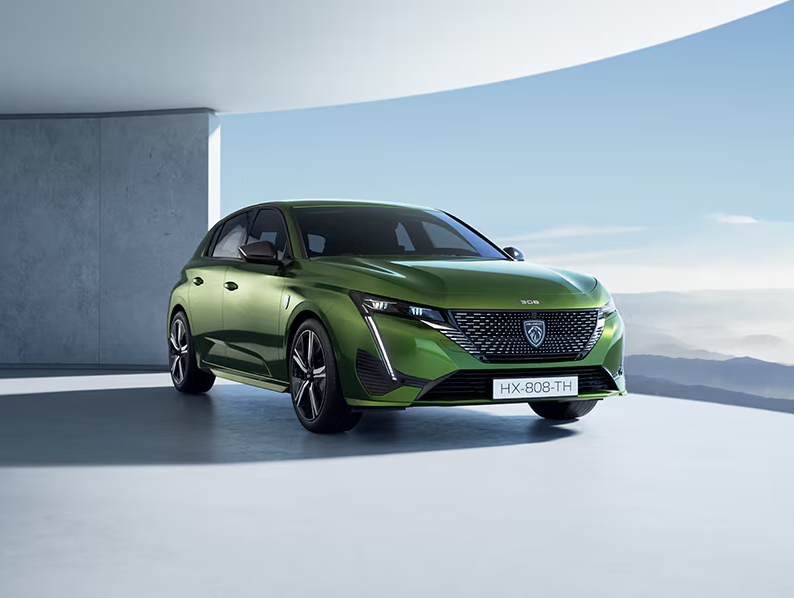 Une Peugeot 308 à hayon verte est garée dans un garage.