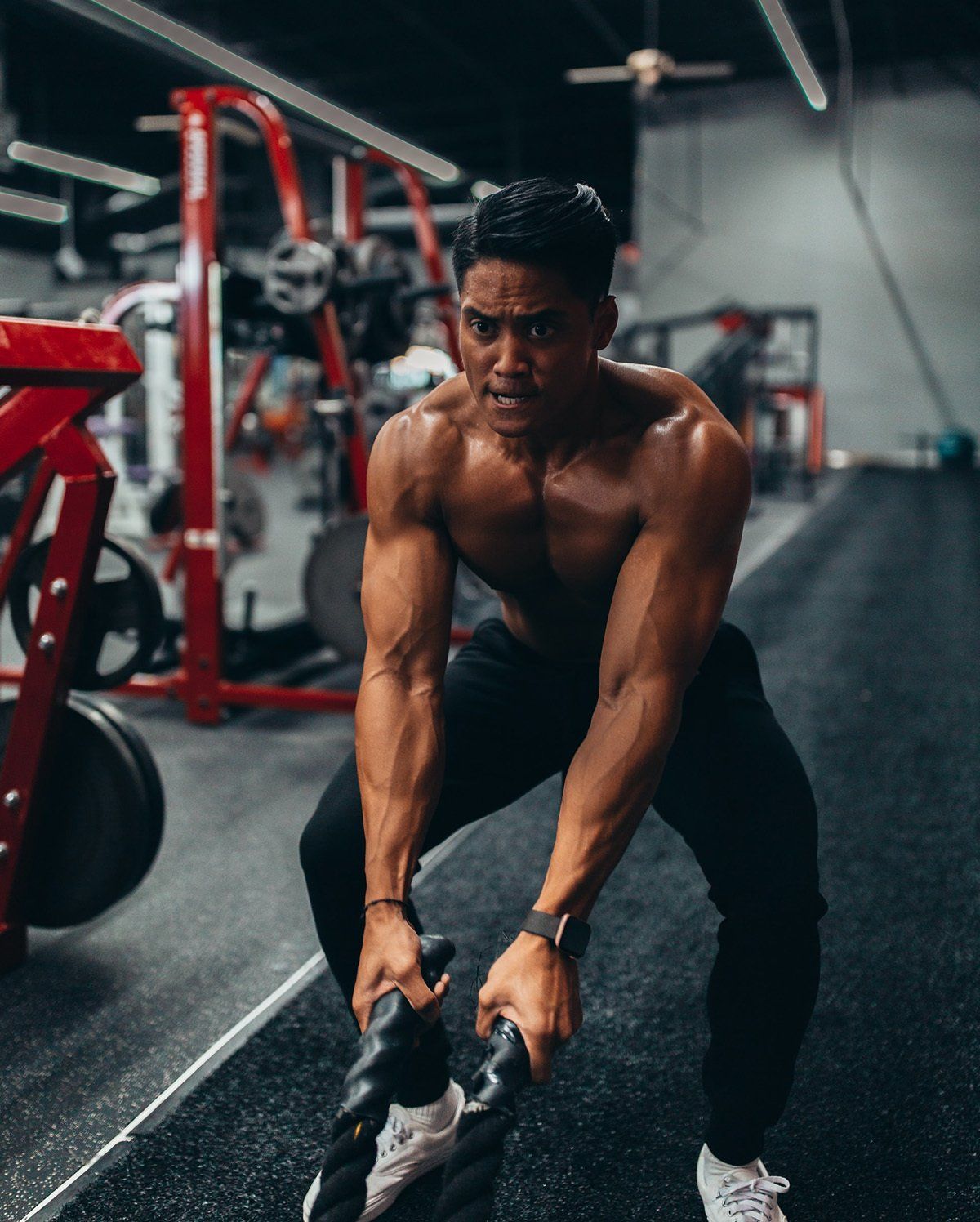 A shirtless man is lifting a barbell in a gym.