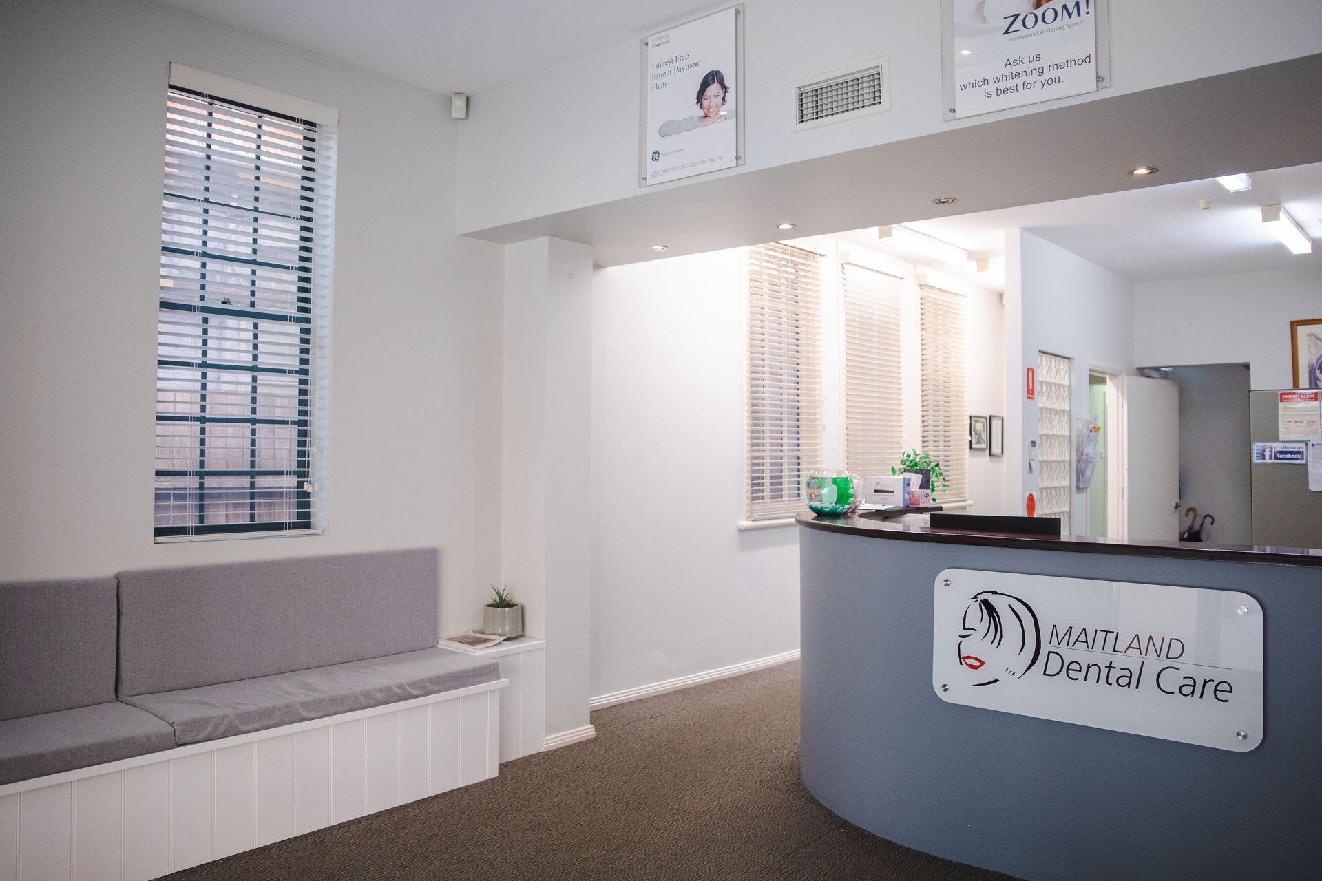A waiting room with a couch and a counter in a dental office — Maitland Dental Care In Maitland NSW