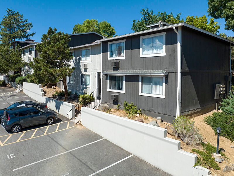Exterior view of a gray two-story apartment building with white trim and a parking lot.