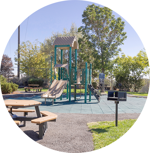 Outdoor playground with slides and climbing structure in a sunny community space.