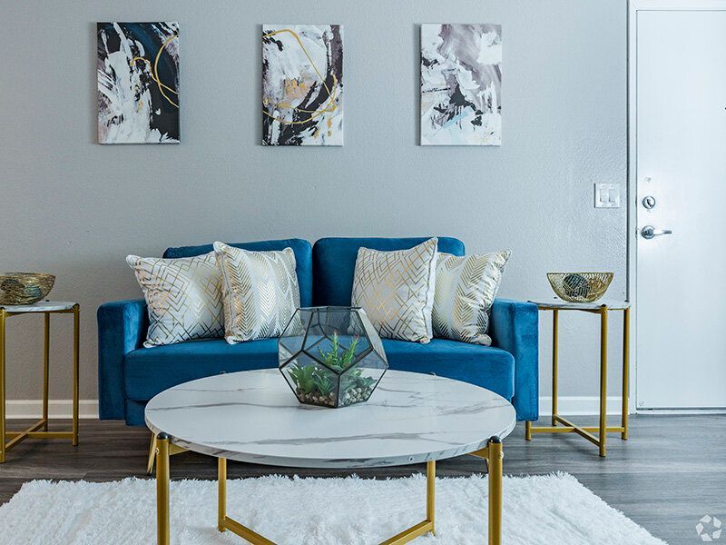 Bright living room with a blue sofa, geometric throw pillows, and a round marble coffee table.