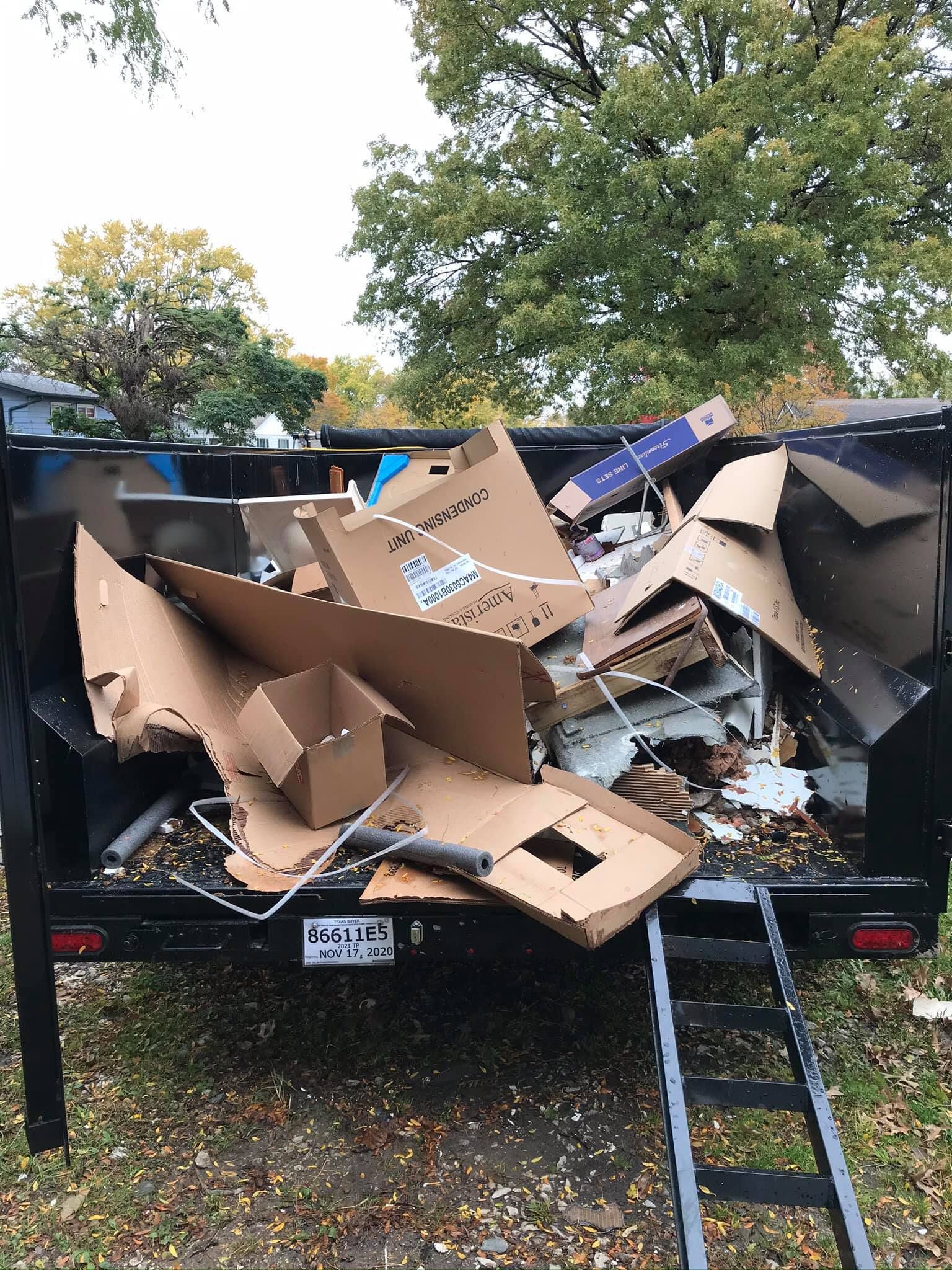 A dumpster filled with a lot of cardboard boxes.
