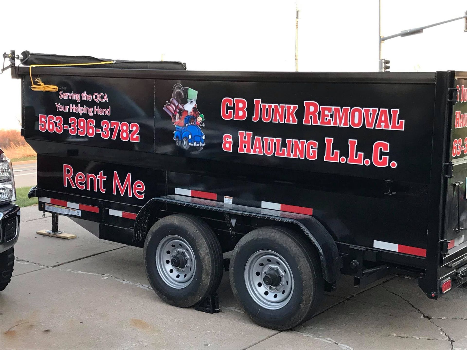 A dumpster trailer for cb junk removal & hauling llc is parked in a parking lot.