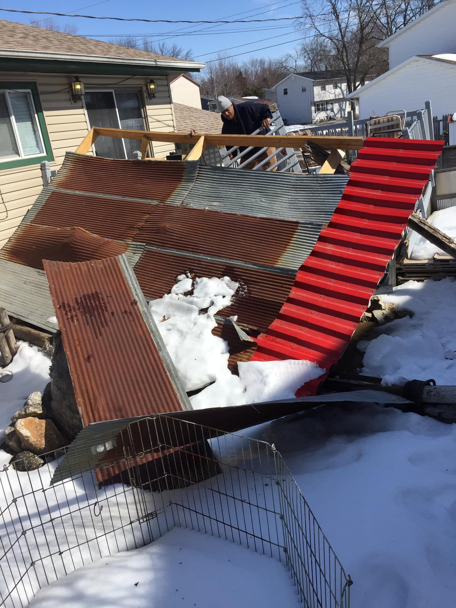 A red chair is sitting in the snow in front of a house