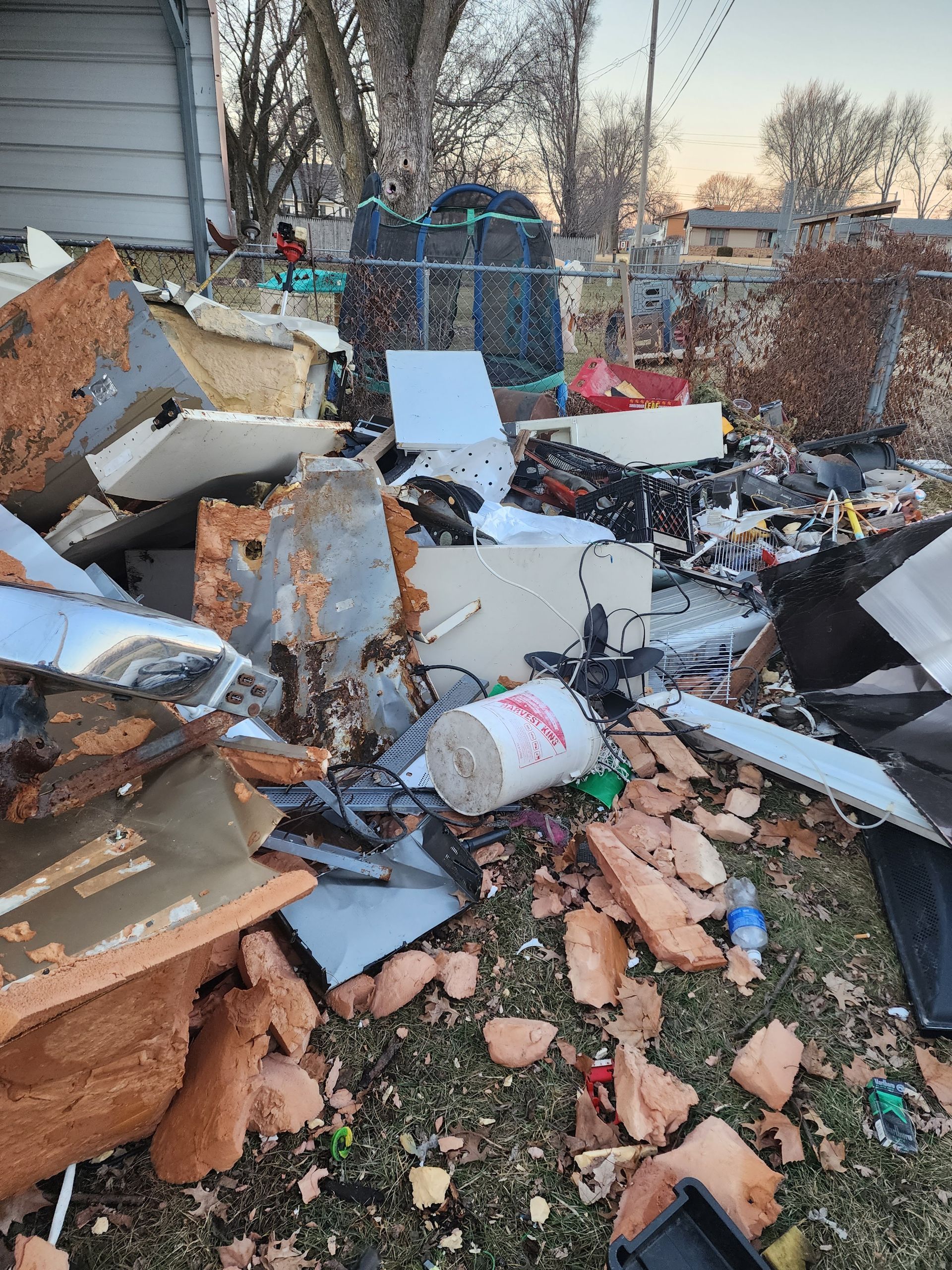 A pile of trash is sitting in the grass in front of a house.