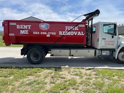 A red junk removal truck is parked on the side of the road.