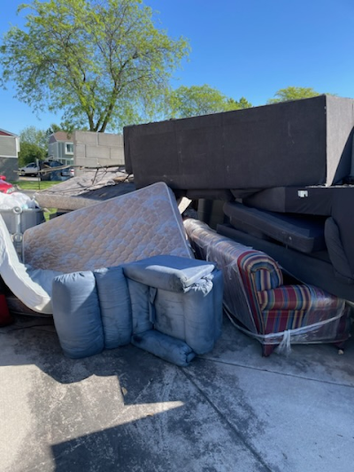 A pile of furniture is sitting on the sidewalk next to a truck.