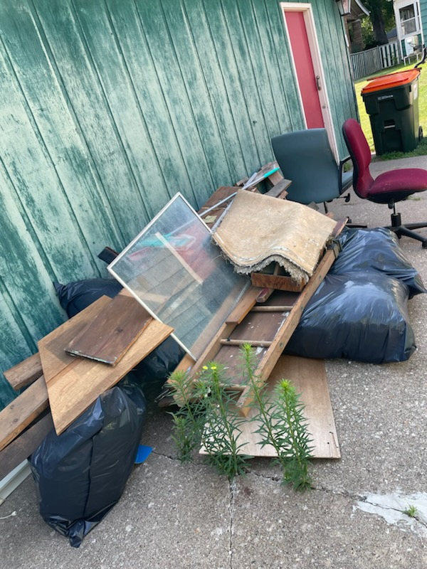 A pile of trash is sitting on the ground in front of a green building.