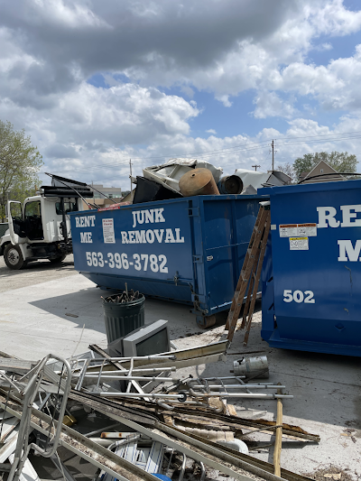 A dumpster filled with junk and a truck parked next to it.