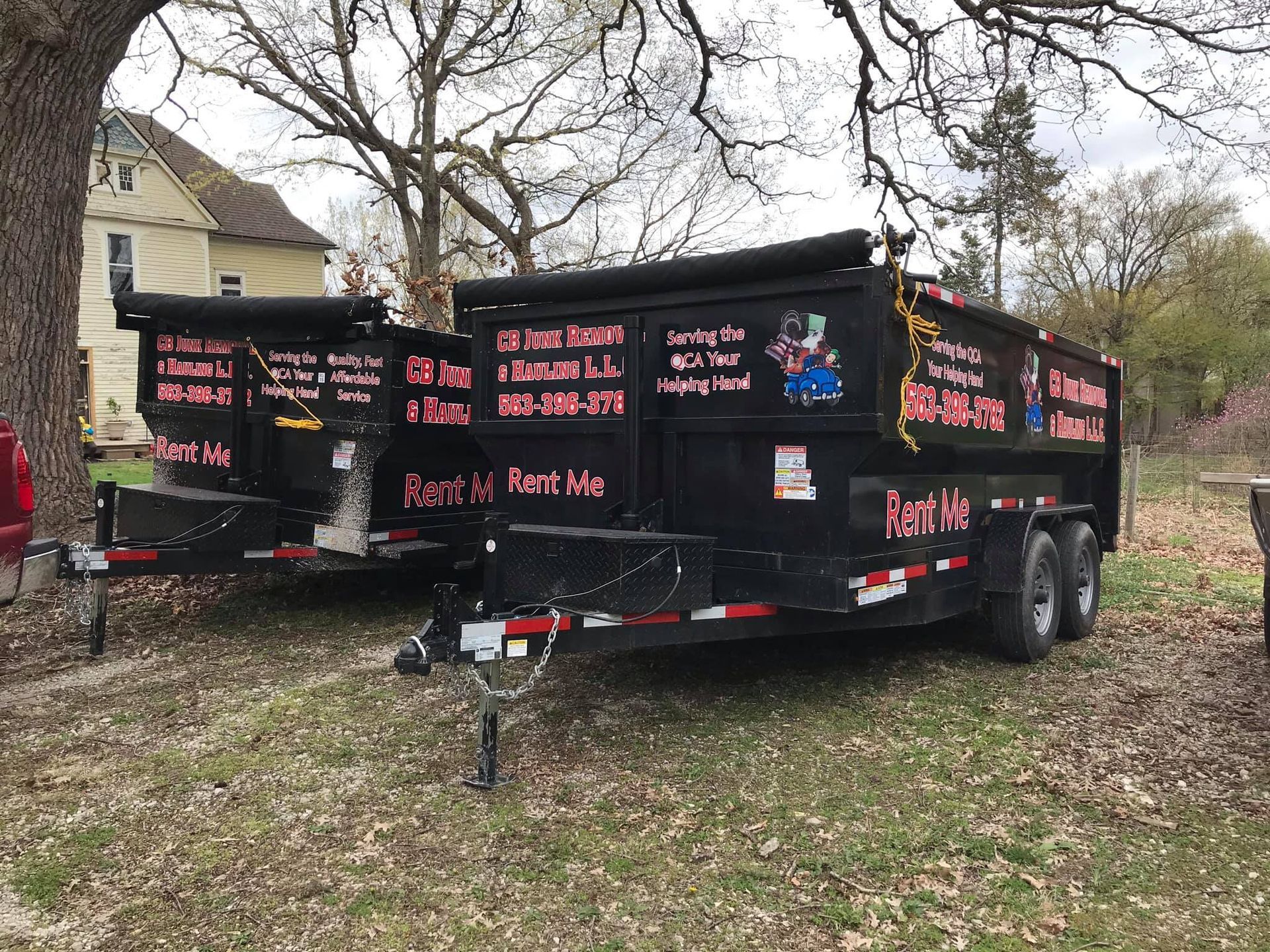 Two dump trailers are parked next to each other in a field.
