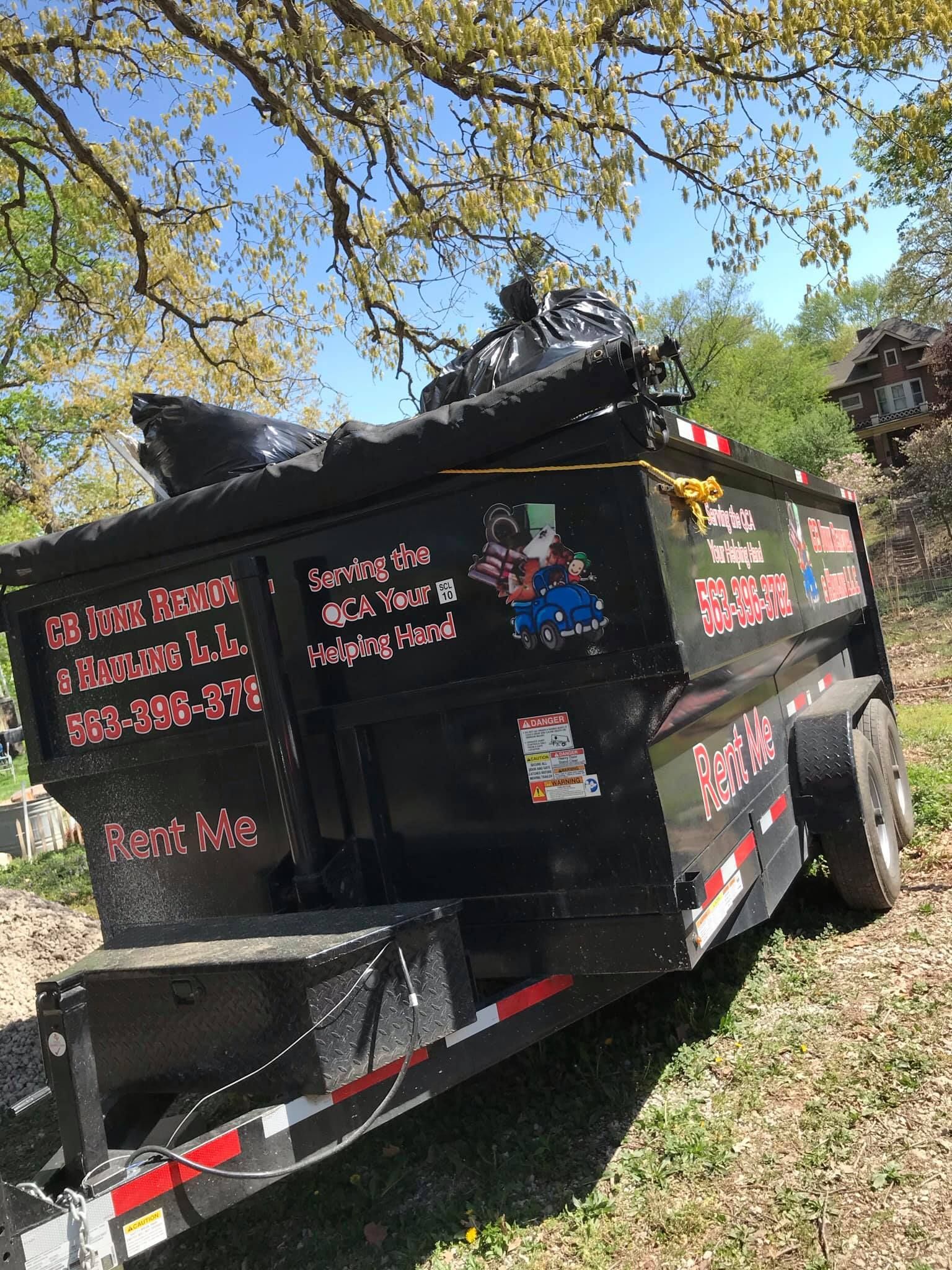 A dumpster trailer is parked in a grassy field.