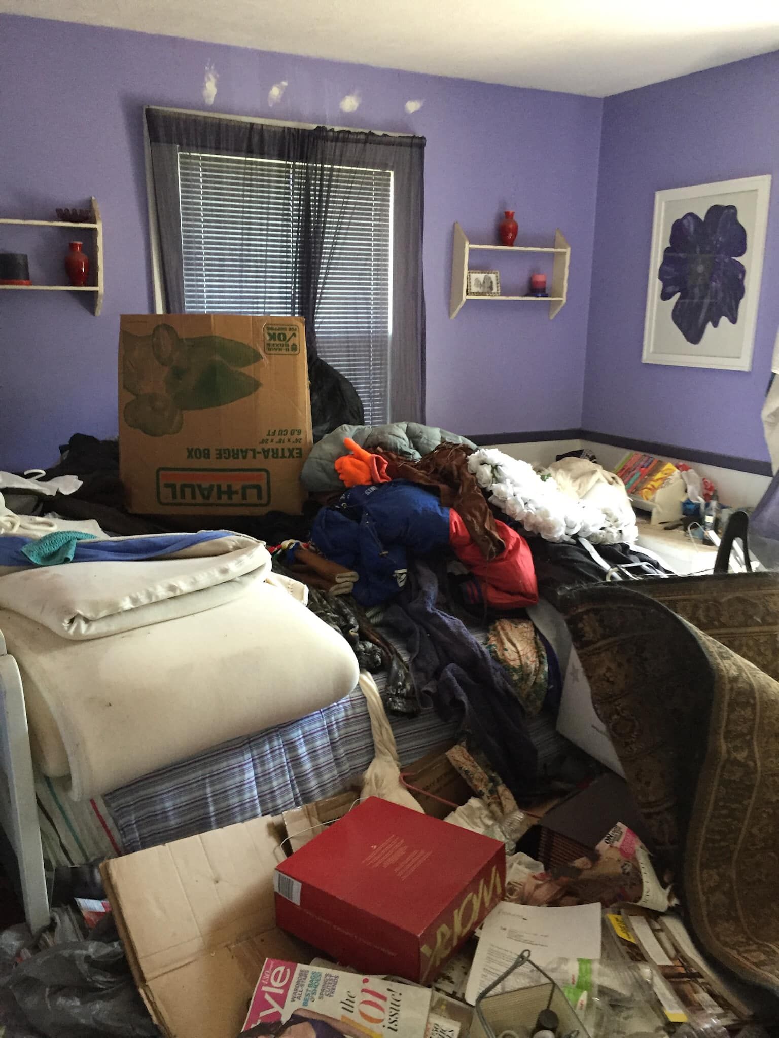 A bedroom with purple walls and a lot of junk on the floor.
