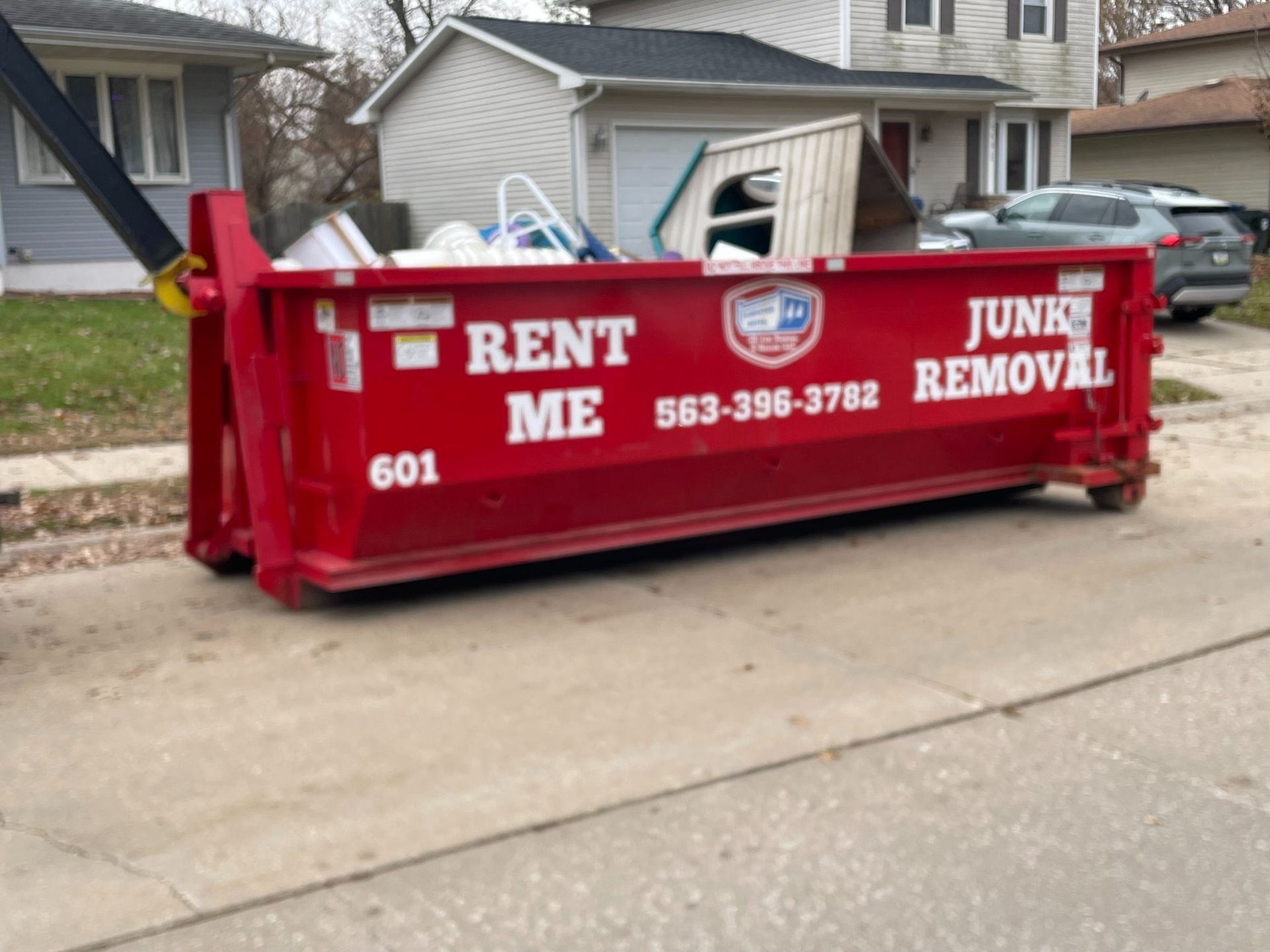 Red dumpster on a street, labeled 