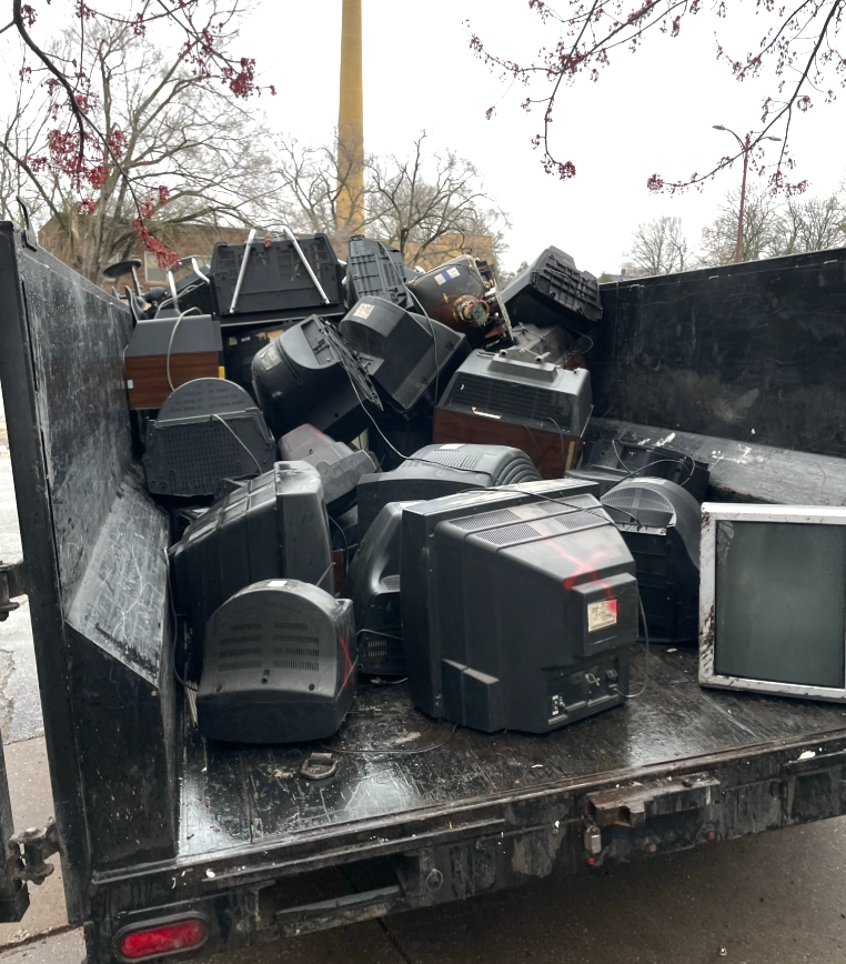 Black pickup truck filled with discarded CRT televisions.