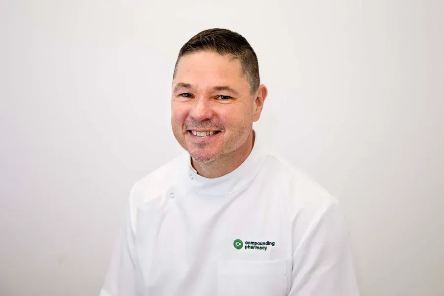 A man in a white coat is smiling for the camera.