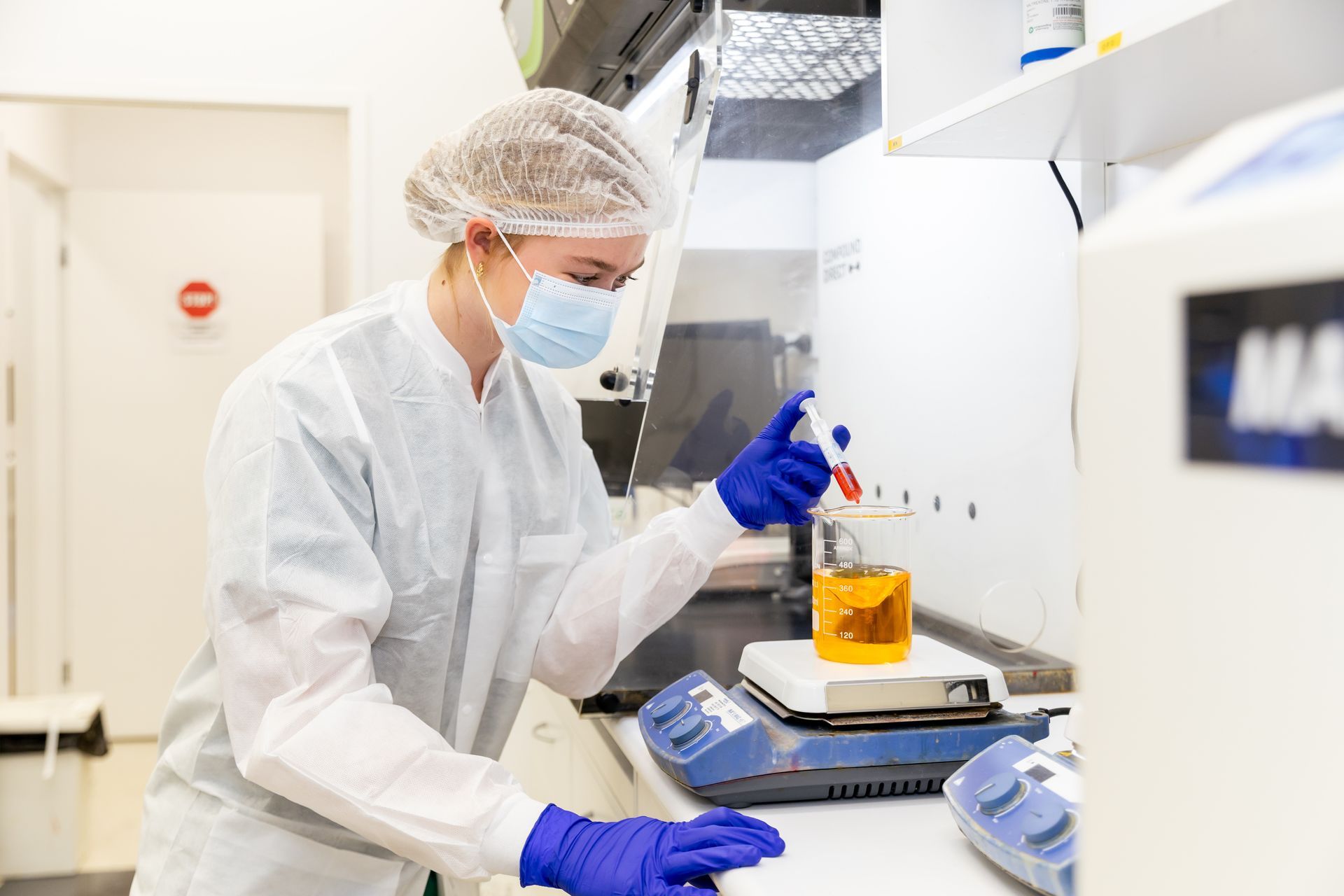 A group of people are standing in a lab talking to each other. A group of people are standing in a lab talking to each other.